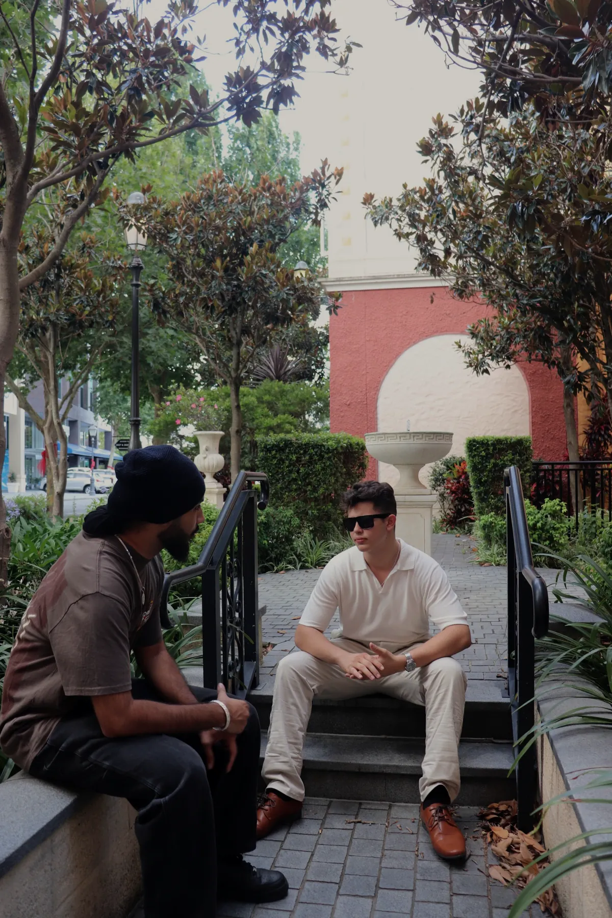 Alex Oliveri sitting on garden steps talking with a friend